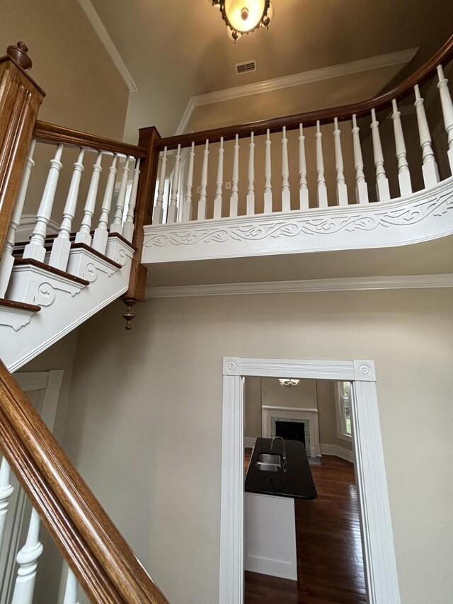 stairs featuring crown molding, sink, and wood-type flooring