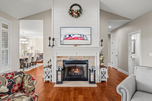 living room with a multi sided fireplace, hardwood / wood-style floors, an inviting chandelier, and lofted ceiling