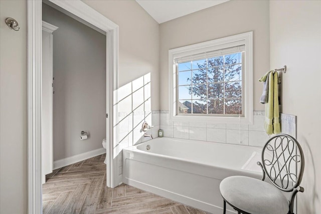 bathroom with a bathtub, toilet, and parquet floors