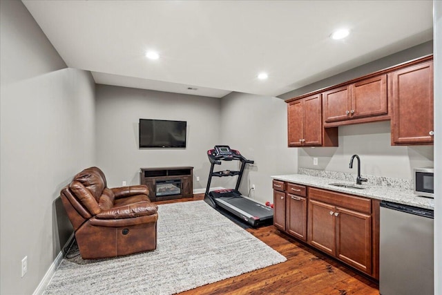 kitchen featuring dark wood-type flooring, sink, a fireplace, light stone counters, and stainless steel appliances