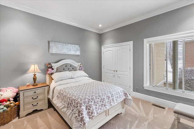 carpeted bedroom with crown molding and a closet