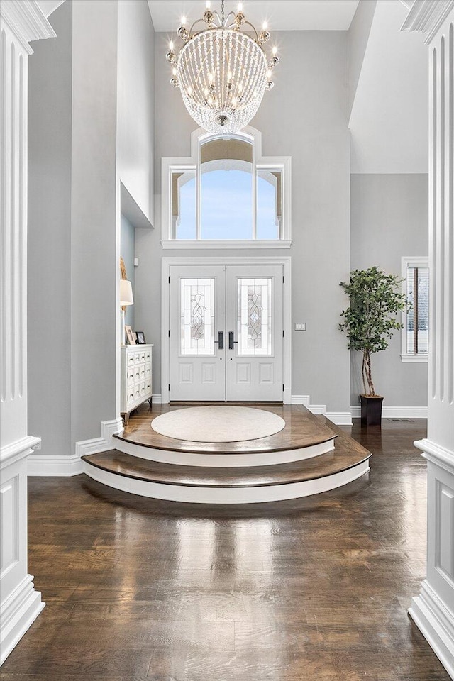 foyer with french doors, a towering ceiling, an inviting chandelier, and a healthy amount of sunlight