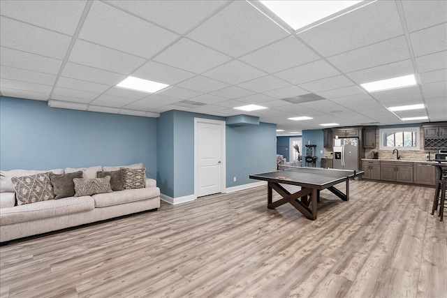 recreation room with light hardwood / wood-style flooring, a drop ceiling, and sink