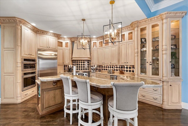 kitchen featuring decorative light fixtures, stainless steel appliances, premium range hood, and a center island with sink