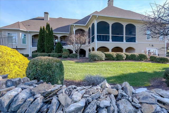 back of house with a lawn and a sunroom