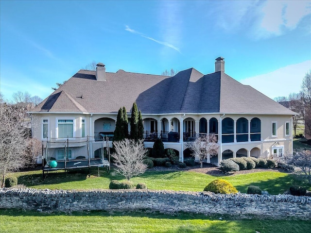 back of property featuring a lawn and a trampoline