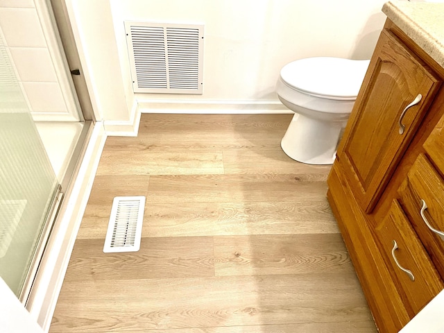 bathroom with toilet, visible vents, wood finished floors, and vanity