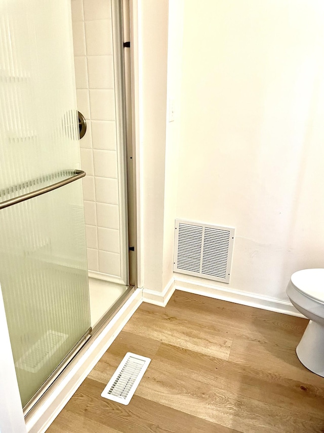 bathroom featuring baseboards, visible vents, toilet, and wood finished floors