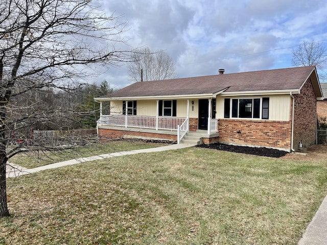 ranch-style home with covered porch, a shingled roof, a front lawn, and brick siding