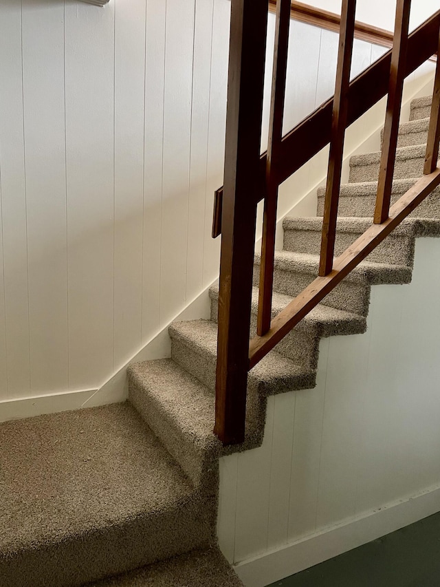 stairway featuring carpet and a decorative wall