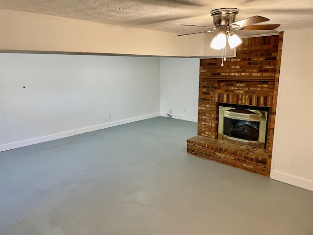 unfurnished living room featuring a ceiling fan, a brick fireplace, a textured ceiling, concrete floors, and baseboards