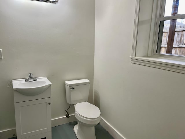 half bath with toilet, baseboards, and vanity