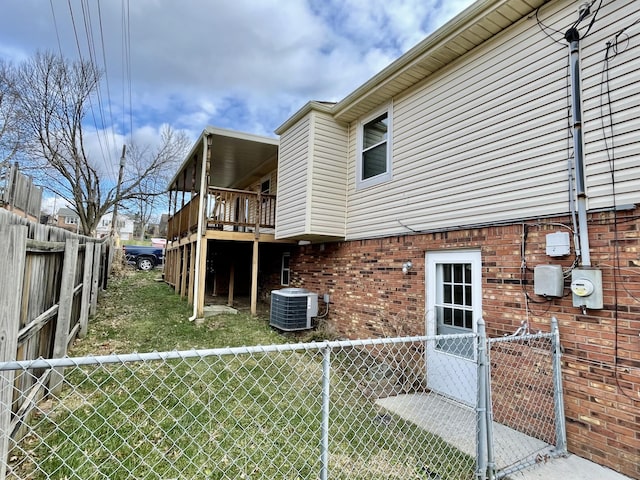 view of side of home with a fenced backyard, central AC, and brick siding