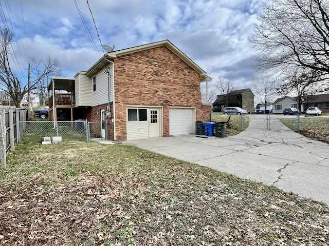 view of side of property with a garage, brick siding, fence, driveway, and a gate