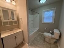 bathroom with a shower, tile patterned flooring, vanity, and toilet