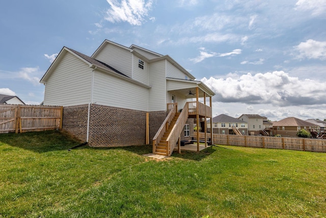 back of property with ceiling fan, a yard, and a deck