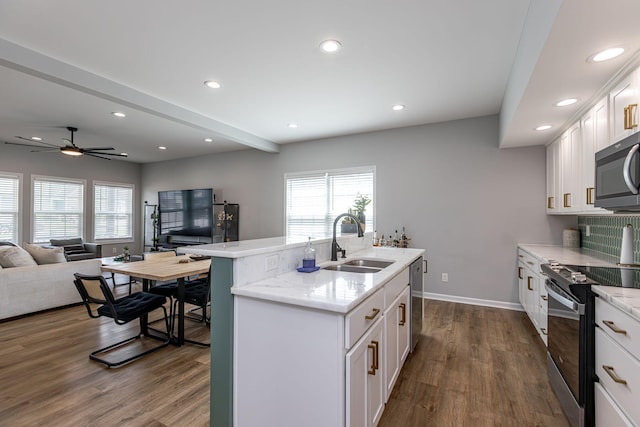 kitchen with sink, dark hardwood / wood-style flooring, an island with sink, white cabinets, and appliances with stainless steel finishes