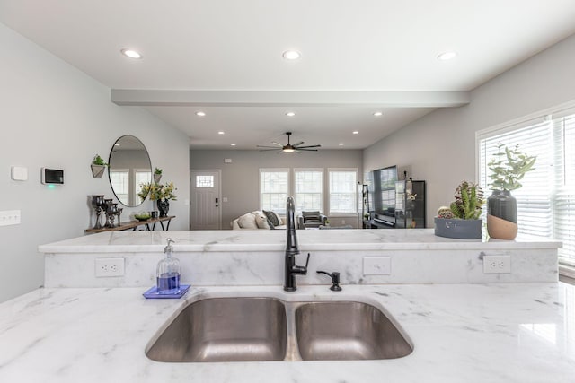 kitchen featuring beam ceiling, light stone countertops, sink, and ceiling fan