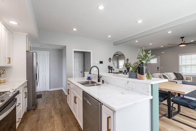 kitchen with a center island with sink, white cabinets, stainless steel appliances, and sink