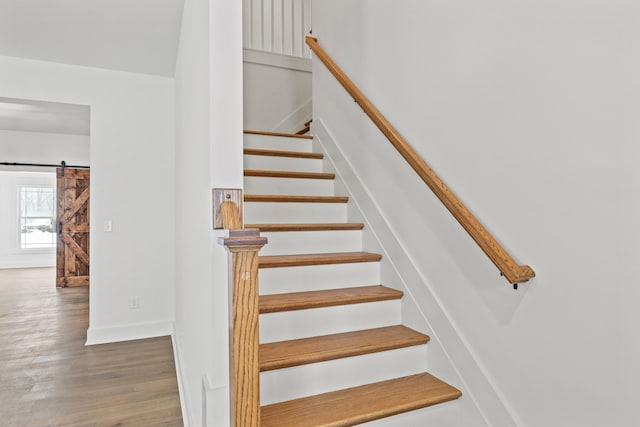 stairway with hardwood / wood-style floors and a barn door