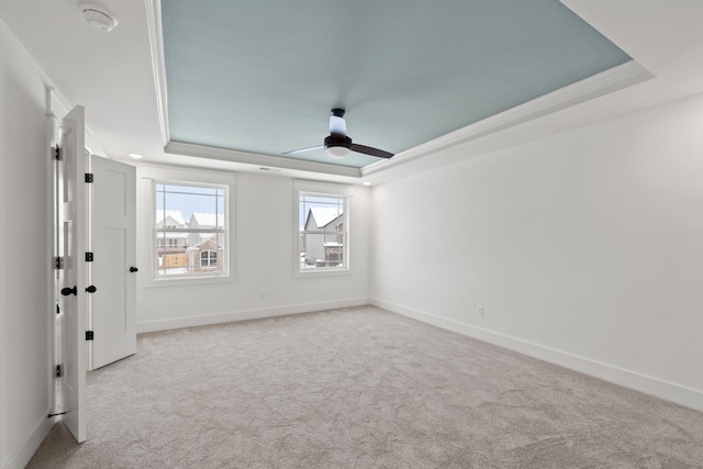 carpeted spare room with ceiling fan, crown molding, and a tray ceiling