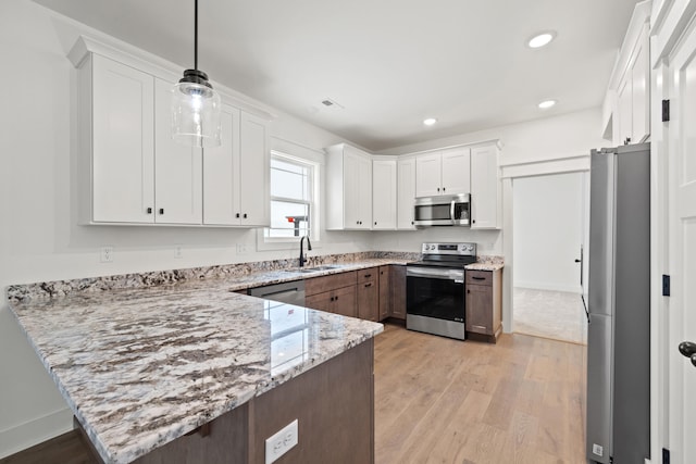 kitchen with light stone countertops, stainless steel appliances, sink, pendant lighting, and white cabinets