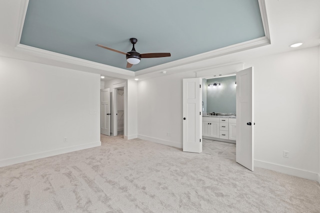 unfurnished bedroom with light colored carpet, a raised ceiling, ceiling fan, crown molding, and connected bathroom