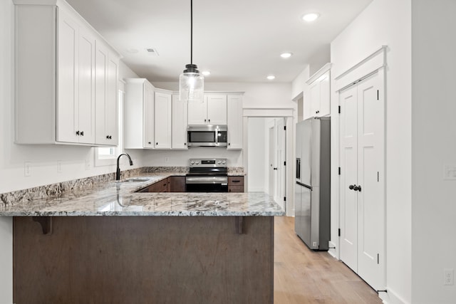 kitchen featuring white cabinetry, sink, hanging light fixtures, kitchen peninsula, and appliances with stainless steel finishes