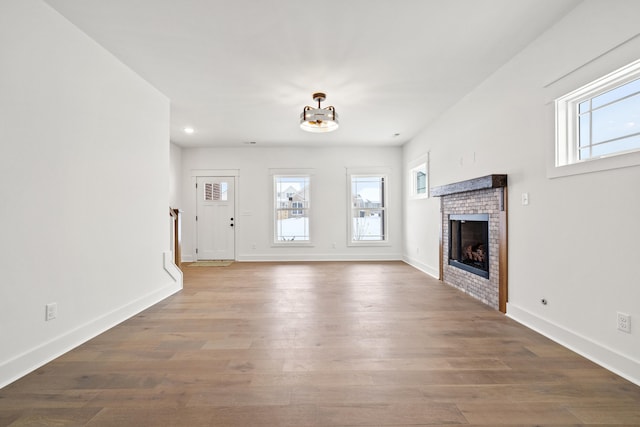 unfurnished living room featuring a fireplace, hardwood / wood-style floors, and an inviting chandelier