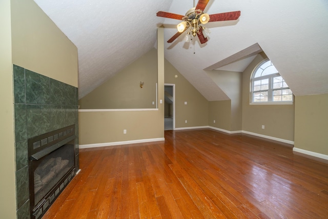 1280 Woodbury Loop, Morgantown, KY 42261 - unfurnished living room featuring a textured ceiling, ceiling fan, a tile fireplace, hardwood / wood-style flooring, and lofted ceiling