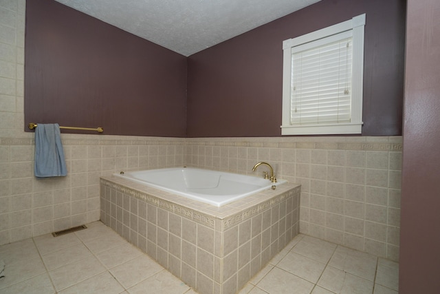 1280 Woodbury Loop, Morgantown, KY 42261 - bathroom featuring tile patterned flooring, a textured ceiling, tiled bath, and tile walls
