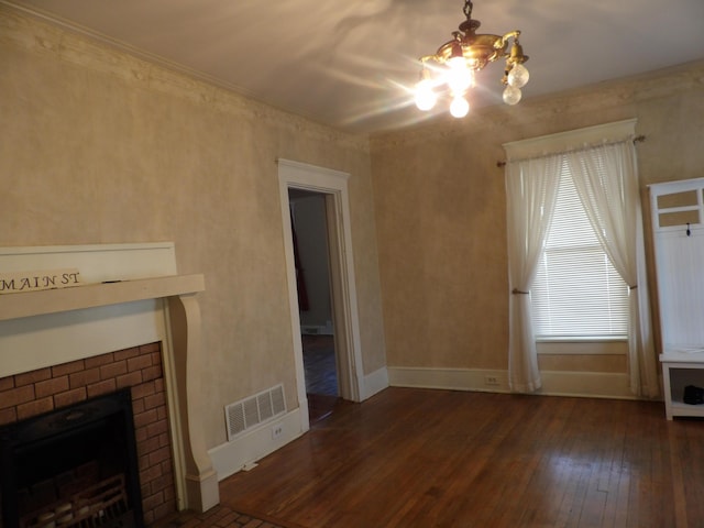 unfurnished living room featuring an inviting chandelier, dark wood-type flooring, and a fireplace