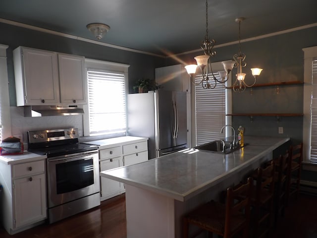 kitchen featuring kitchen peninsula, white cabinets, a breakfast bar area, and stainless steel appliances