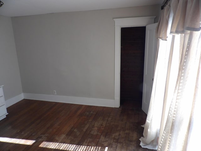 unfurnished room with dark wood-type flooring