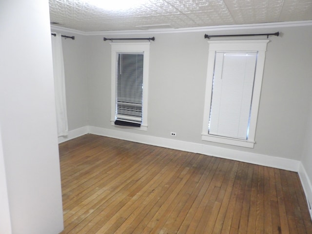 empty room featuring wood-type flooring and ornamental molding