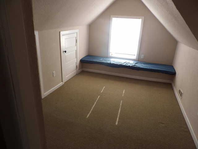 unfurnished bedroom featuring carpet, a textured ceiling, and vaulted ceiling