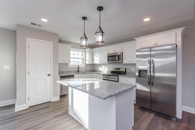 kitchen featuring sink, white cabinets, pendant lighting, a kitchen island, and appliances with stainless steel finishes