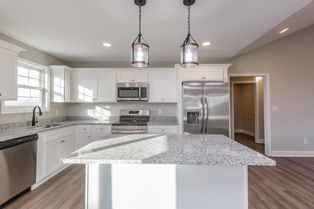 kitchen with a center island, sink, decorative light fixtures, white cabinetry, and stainless steel appliances