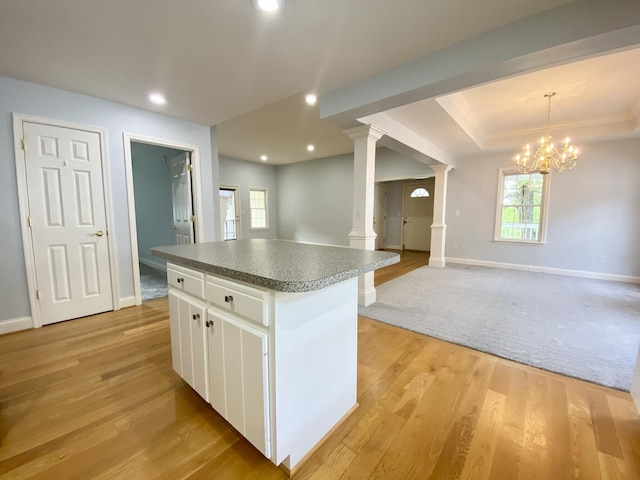 kitchen with ornate columns, an inviting chandelier, white cabinets, a kitchen island, and hanging light fixtures