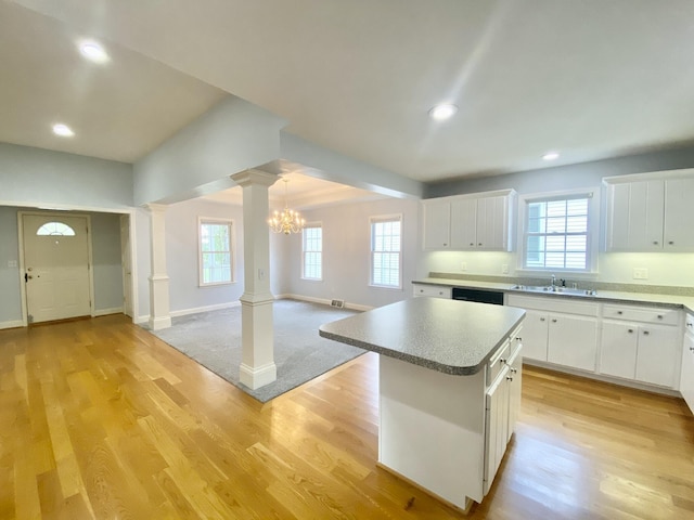 kitchen with white cabinetry, a center island, sink, decorative columns, and a chandelier