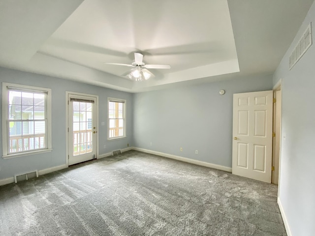 unfurnished room with carpet floors, a tray ceiling, and ceiling fan