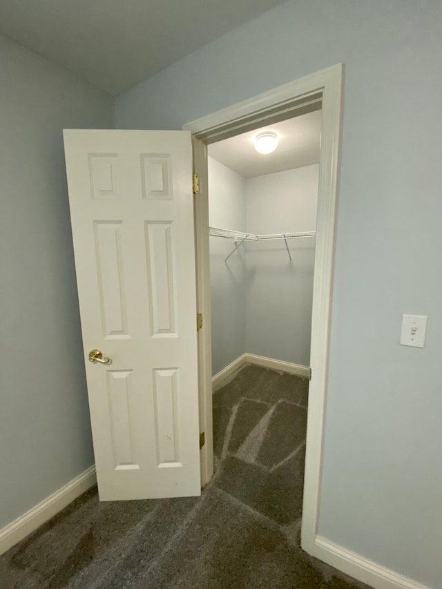 walk in closet featuring dark colored carpet