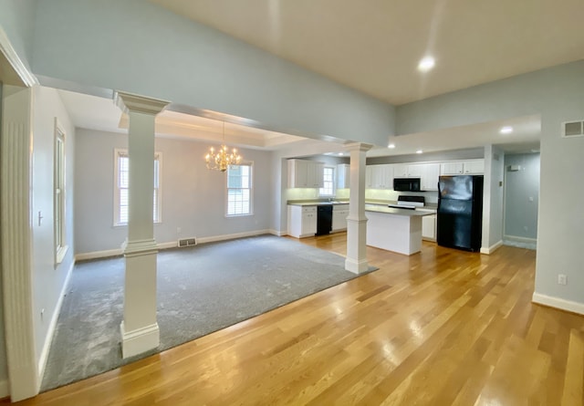 kitchen with an inviting chandelier, black appliances, hanging light fixtures, a kitchen island, and white cabinetry