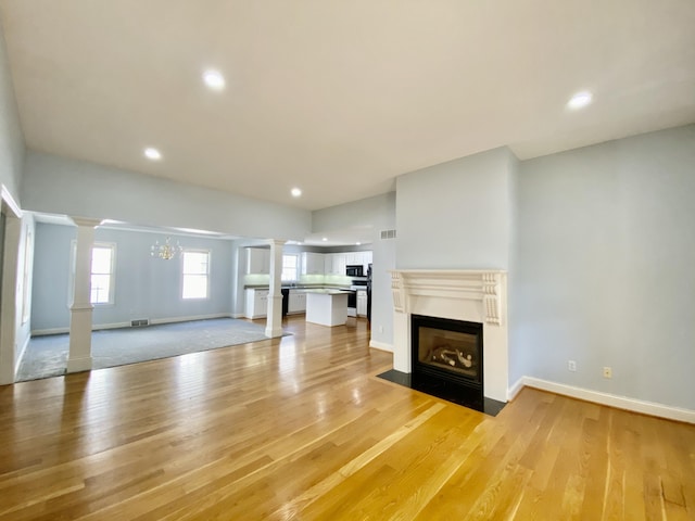 unfurnished living room with light wood-type flooring and a notable chandelier