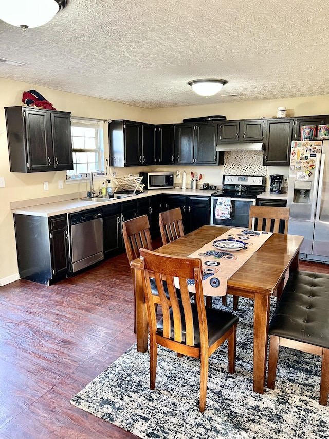 kitchen featuring sink, backsplash, wood-type flooring, a textured ceiling, and appliances with stainless steel finishes