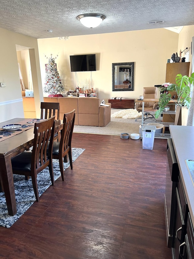 dining area with a textured ceiling and dark wood-type flooring