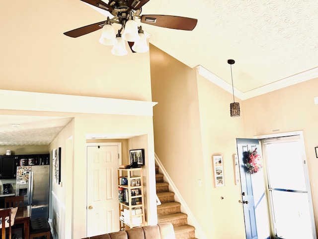 staircase with a textured ceiling, high vaulted ceiling, ceiling fan, and crown molding