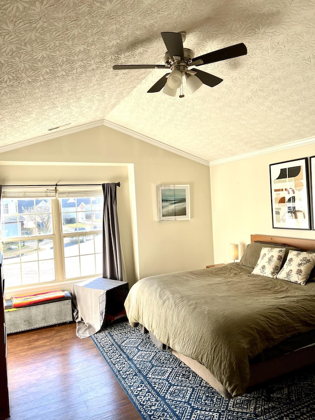 bedroom with hardwood / wood-style floors, lofted ceiling, ceiling fan, ornamental molding, and a textured ceiling