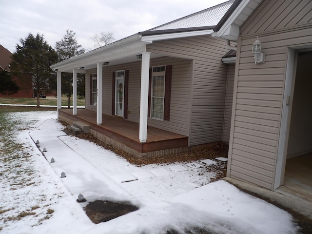 snow covered property with covered porch