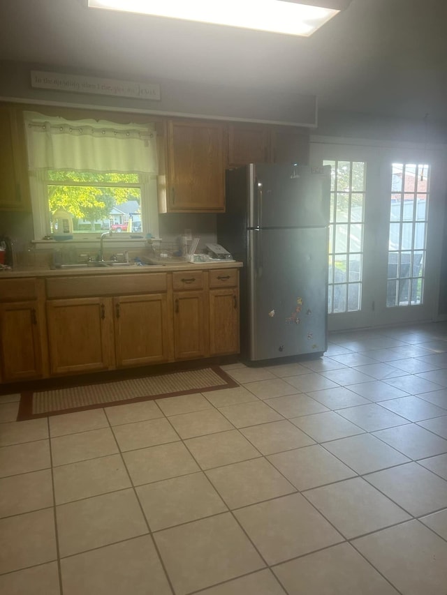 kitchen with stainless steel fridge, sink, and light tile patterned floors